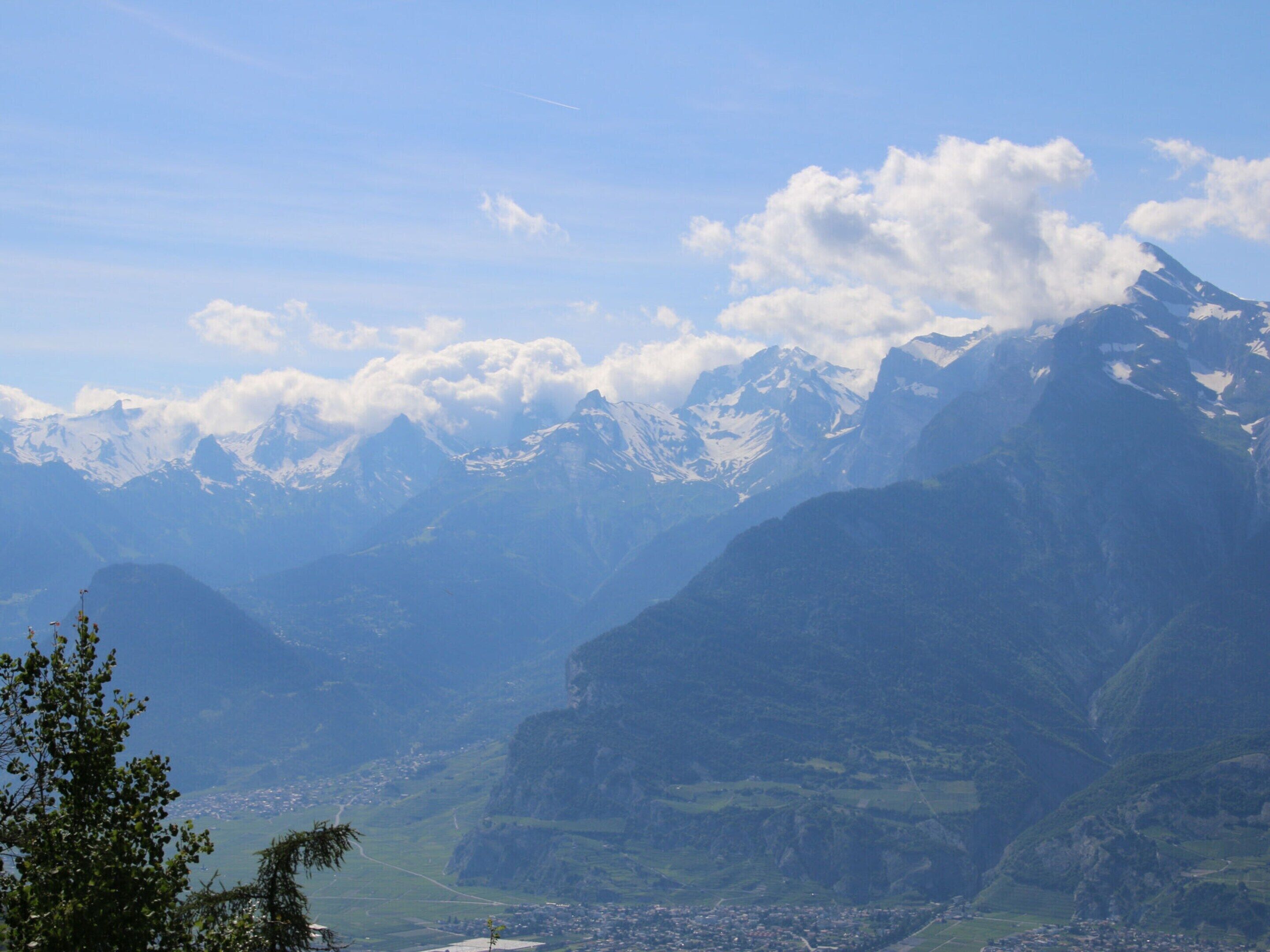 A mountainous landscape with snow-capped peaks and a valley with a small town.