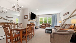 A spacious living room with a dining area, leather sofas, a TV, and a chandelier. - Gorgeous 3BR Ski-In/Ski-Out Condo at Okemo (Ludlow)