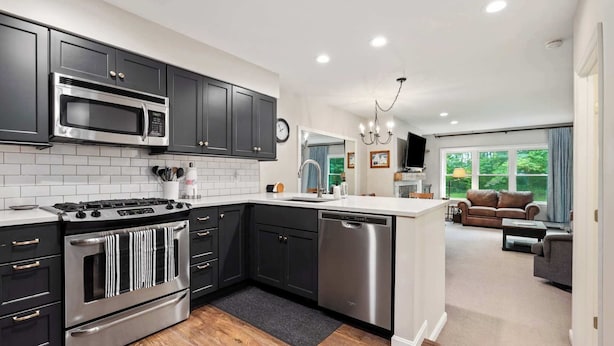 A modern kitchen with dark cabinets, stainless steel appliances, and a central island. - Gorgeous 3BR Ski-In/Ski-Out Condo at Okemo (Ludlow)