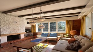 A modern living room with a fireplace, a sofa set, a dining table, and a large window with curtains. - Cache-cache Mountain & Quiet Chalet 10 Pers (Nendaz)