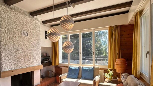 A cozy living room with a fireplace, a sofa, a coffee table, and a view of the outdoors through large windows. - Cache-cache Mountain & Quiet Chalet 10 Pers (Nendaz)