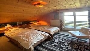 A cozy room with wooden ceilings and a large window. There are two beds with white linens and a single chair. - Cache-cache Mountain & Quiet Chalet 10 Pers (Nendaz)
