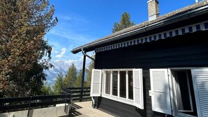 A building with a black exterior and white shutters, a chimney, and a view of mountains. - Cache-cache Mountain & Quiet Chalet 10 Pers (Nendaz)