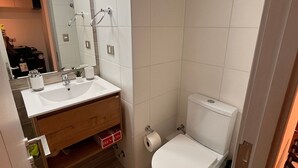 Une salle de bain avec un lavabo blanc, un miroir et des toilettes.