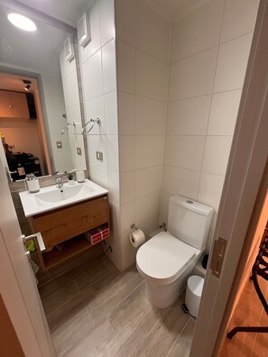 A bathroom with a white sink, mirror, and toilet. - Oceana Suites Eco España (Santiago)