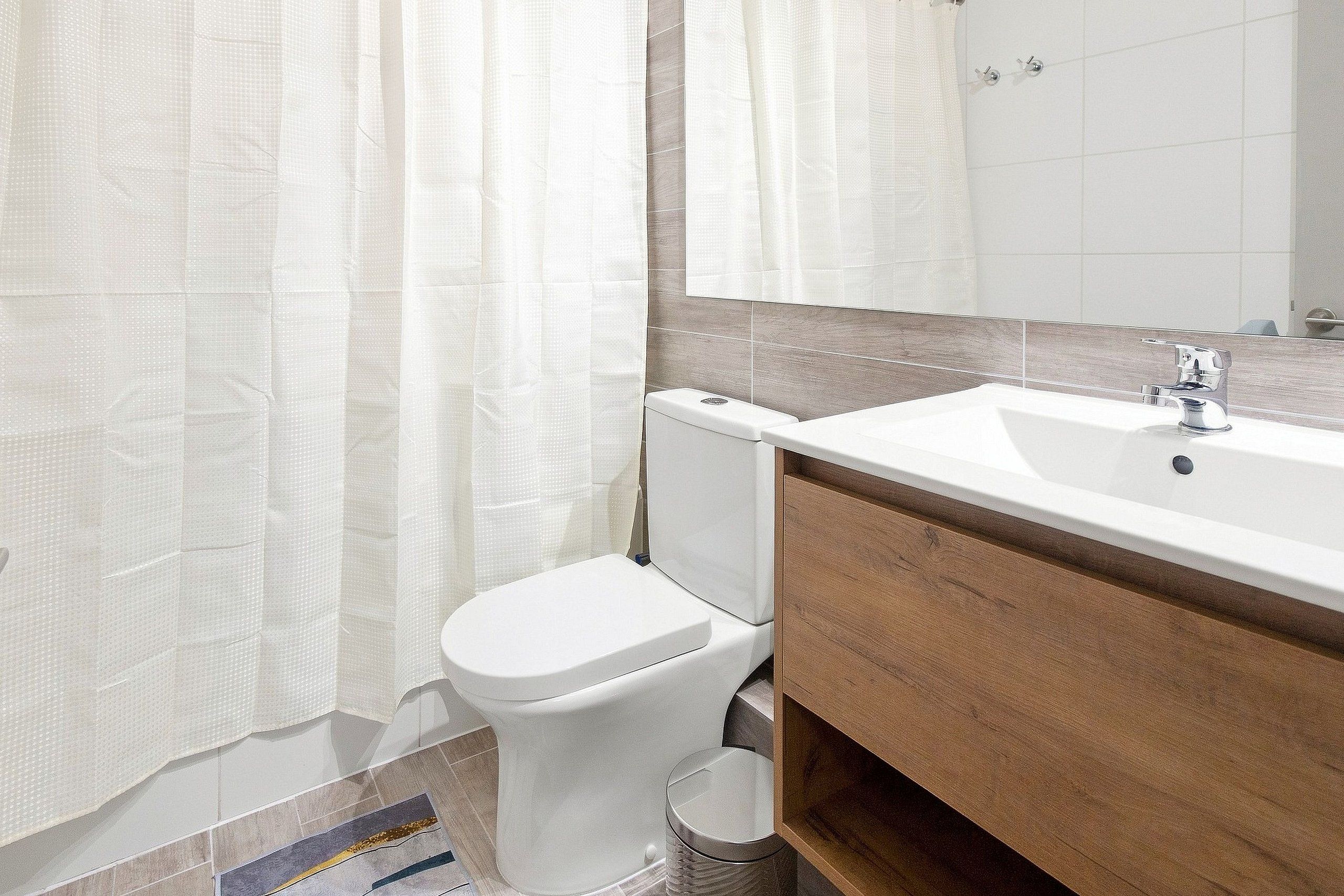 A bathroom with a white toilet, a sink, and a mirror.