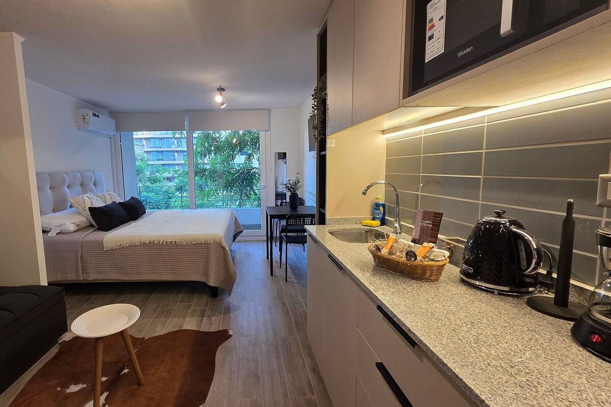 Een knus hotelkamer met een bed, een zithoekje, een kitchenette en uitzicht op de omgeving.
