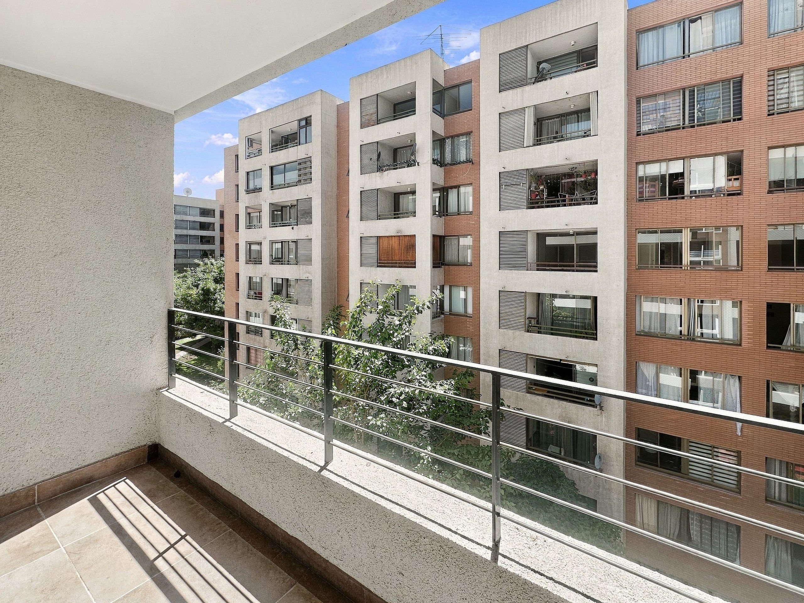 Un moderno edificio de apartamentos con balcones, ventanas amplias y cielo despejado.