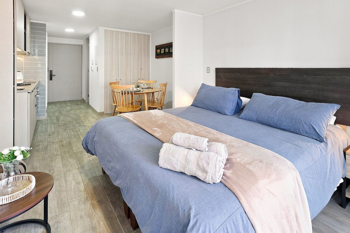 Une chambre d’hôtel comprenant un lit, une table de chevet, une lampe et un coin repas avec des chaises et une table.