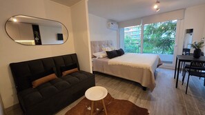Une chambre moderne avec un lit, un canapé, une table à manger et une grande fenêtre.