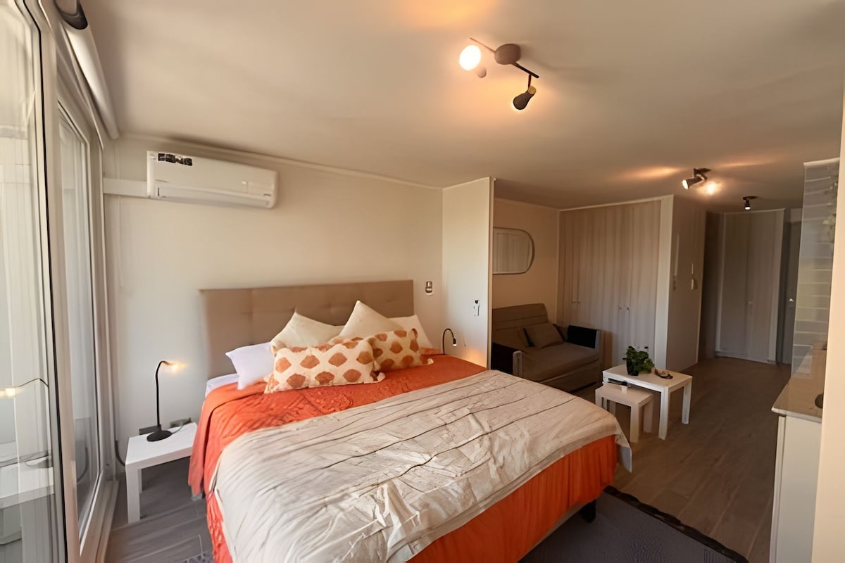 Une chambre d’hôtel moderne, dotée d’un grand lit, d’un bureau et d’une petite table.