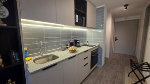 Een moderne keuken met een roestvrijstalen spoelbak, een koffiezetapparaat en een inbouwoven.
