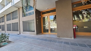 A building entrance with a glass door, metal bars on windows, and a fire hydrant outside. - Oceana Suites Eco España (Santiago)