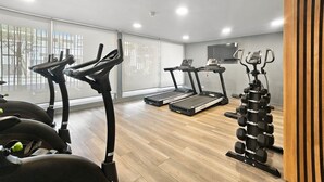 Une salle de sport à domicile équipée de matériel d’exercice, notamment un tapis de course, un vélo elliptique et des haltères.