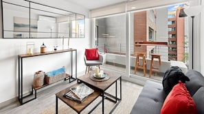 Un salon moderne avec un canapé, une table basse et un coin repas donnant sur un balcon.