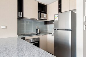 A modern kitchen with stainless steel appliances, a microwave, and a kettle on the countertop.