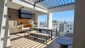 Un balcon moderne doté d’un espace repas, d’une cuisine intégrée et offrant une vue sur la ville.