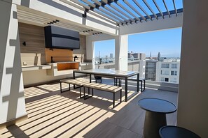 Un balcon moderne doté d’un espace repas, d’une cuisine intégrée et offrant une vue sur la ville.