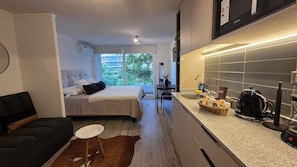Une chambre d’hôtel compacte comprenant un lit, un petit coin salon, une kitchenette et une vue sur l’extérieur.