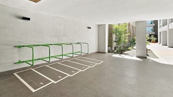 Un área de estacionamiento con espacios delimitados y un aparcamiento de metal verde para bicicletas.