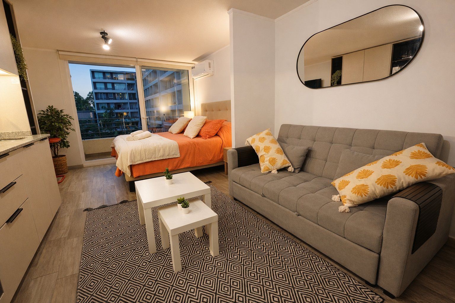 Quarto moderno com cama, sofá, mesinha e espelho.