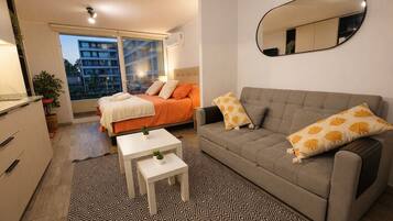 Quarto moderno com cama, sofá, mesinha e espelho.