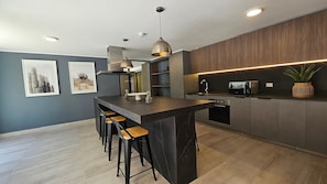 Una cocina moderna con una isla central, taburetes de bar, un microondas y un lavaplatos.