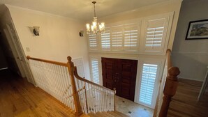 A wooden staircase with a white railing, a chandelier, and a door with shutters. - Spacious 4-bed house in the woods of beautiful Monument by the Air Force Academy (Monument)