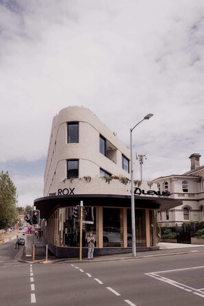 A modern building with a curved facade, named "The Rox," featuring large windows and a street-level entrance. - The Rox - Inner City Luxury (Hobart)