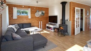 Una sala de estar moderna con un sofá modular, un televisor, una chimenea y paredes de madera.