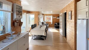 Una cabaña espaciosa y bien iluminada con una larga mesa de comedor, paredes de madera y una cocina moderna.