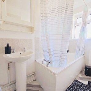 Ein Badezimmer mit einem weißen Waschbecken, einer Badewanne und einem gestreiften Duschvorhang.
