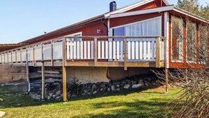 A two-story house with a wooden deck and a stone foundation. - 6 Person Holiday Home in Valdermarsvik (Gryt)