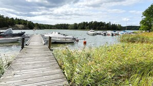A wooden dock leading to a calm lake with boats docked, surrounded by dense forest. - 6 Person Holiday Home in Valdermarsvik (Gryt)