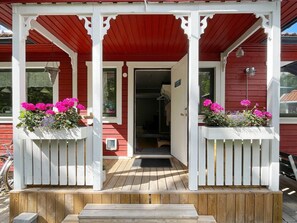 A wooden porch with a red roof and white columns, leading to a door with a small window. - 6 Person Holiday Home in Valdermarsvik (Gryt)