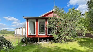 A red house with a small porch, a window, and a chimney.