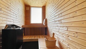 Ein Saunaraum mit Holzwänden, einer Sitzbank, einem Eimer und einer Heizung.