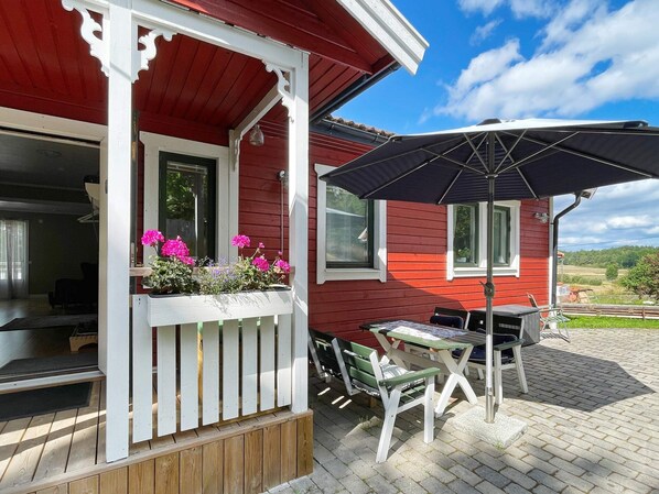 A red house with a porch, a table, chairs, and an umbrella. - 6 Person Holiday Home in Valdermarsvik (Gryt)