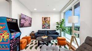 A modern living room with a sofa, armchairs, a coffee table, and a large window offering a city view.