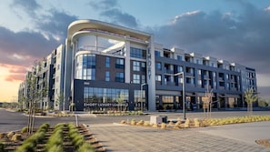 A modern multi-story building with a curved facade, large windows, and a sign for 'Emory Luxury Leasing'.