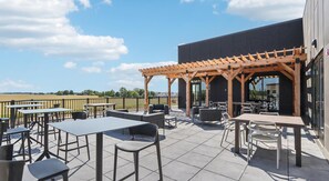 Eine Außenpatio mit Tischen und Stühlen, eine Holzpergola und Blick auf die Landschaft.