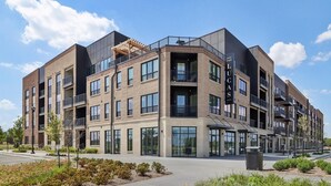 Un edificio de varios pisos con un diseño arquitectónico moderno, que cuenta con ventanas grandes y balcones.