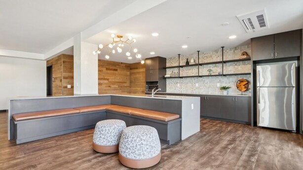 Una cocina moderna con una isla integrada, muebles color gris y marrón, un refrigerador de acero inoxidable y una lámpara de techo original.