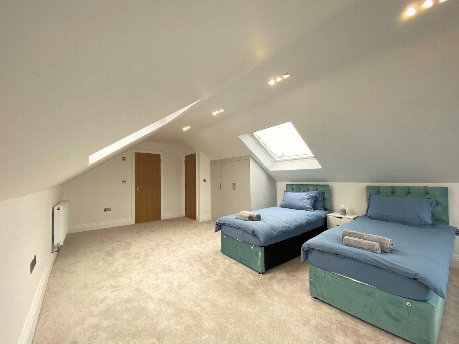Een slaapkamer met twee bedden, een dakraam en een vloerbedekking.