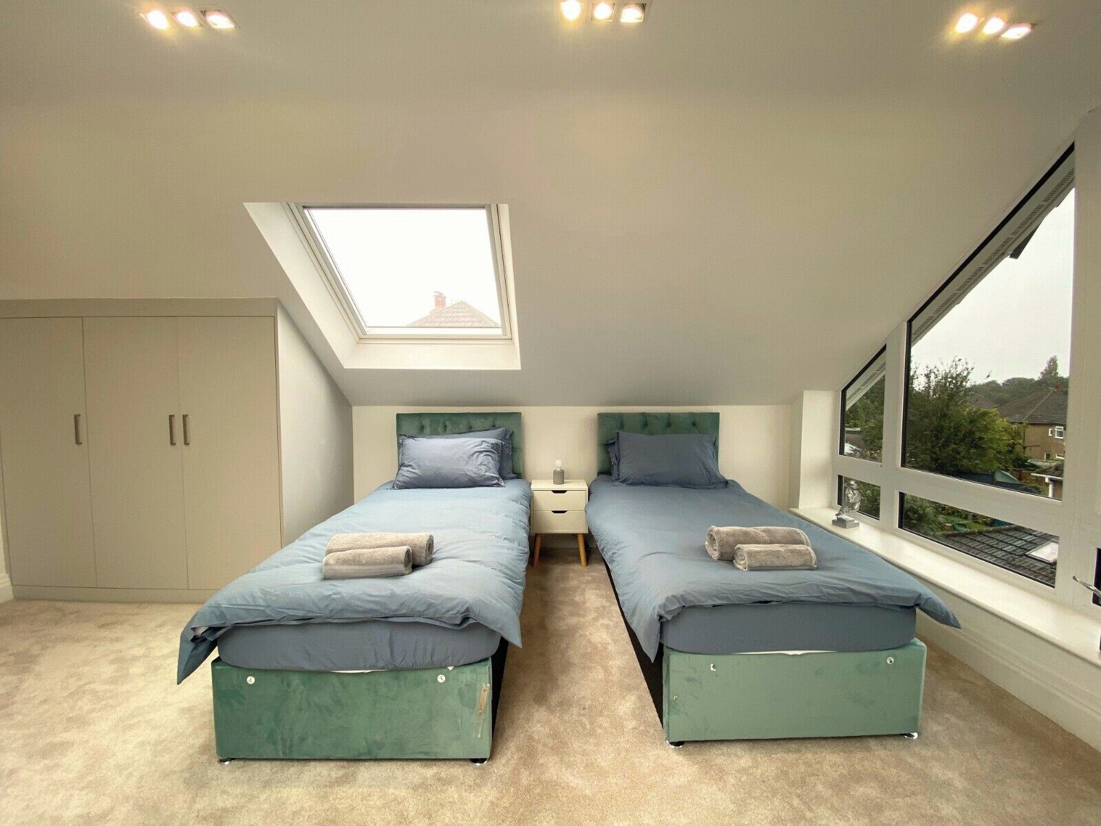 Ein Schlafzimmer mit zwei Betten, einem Oberlicht, einem Kleiderschrank und einem großen Fenster.