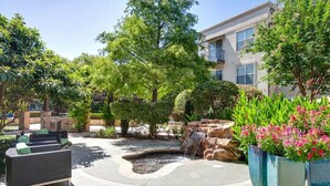 A courtyard with a small waterfall, outdoor seating, and potted plants. - Landing | Stunning Studio, Courtyard, Pool (Dallas)