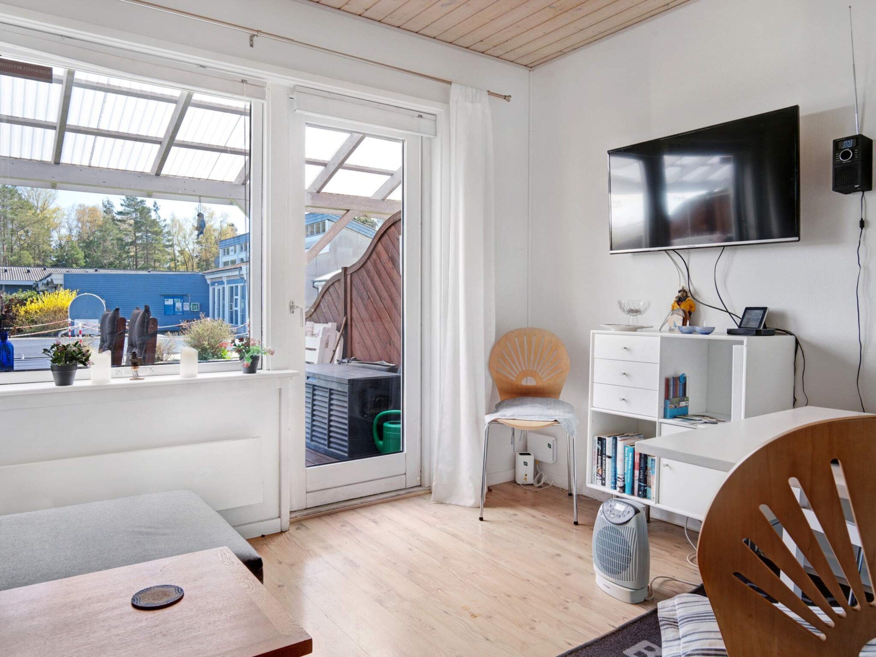 A modern room with a TV, bookshelf, and a view through a glass door.