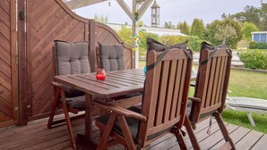 A wooden deck with a table and chairs, a wooden gate, and a pergola with a bird and owl decoration. - 2 Person Holiday Home in Nexo (Nexø)