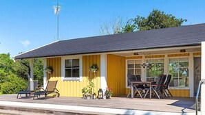 Ein gelbes Gebäude mit einer Veranda, Außenplätzen und einer Satellitenschüssel.