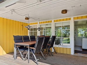 An outdoor patio with a wooden table and chairs, a ceiling fan, and a view of the outdoors.